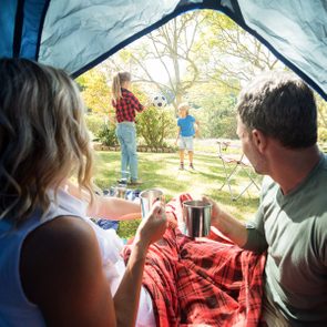 Rear view of couple having coffee and looking at kids playing outside the tent; Shutterstock ID 635870486; Job (TFH, TOH, RD, BNB, CWM, CM): TOH