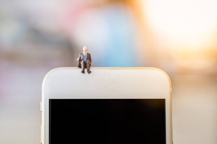 Business, technology concept. Businessman miniature tiny figure toy sit on the top of smart phone with copy space