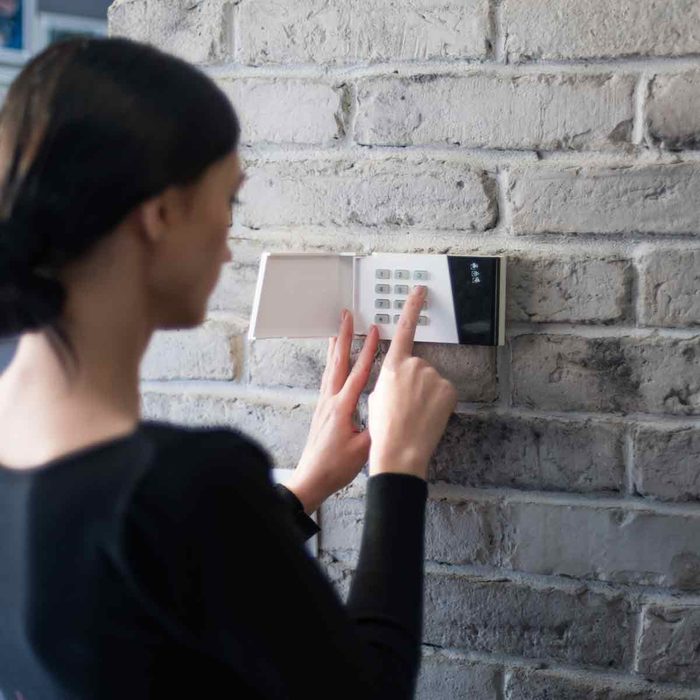 Young-woman-entering-security-pin-on-home-alarm-keypad