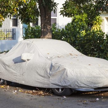 Car under a protective cover parked on the roadside in the city