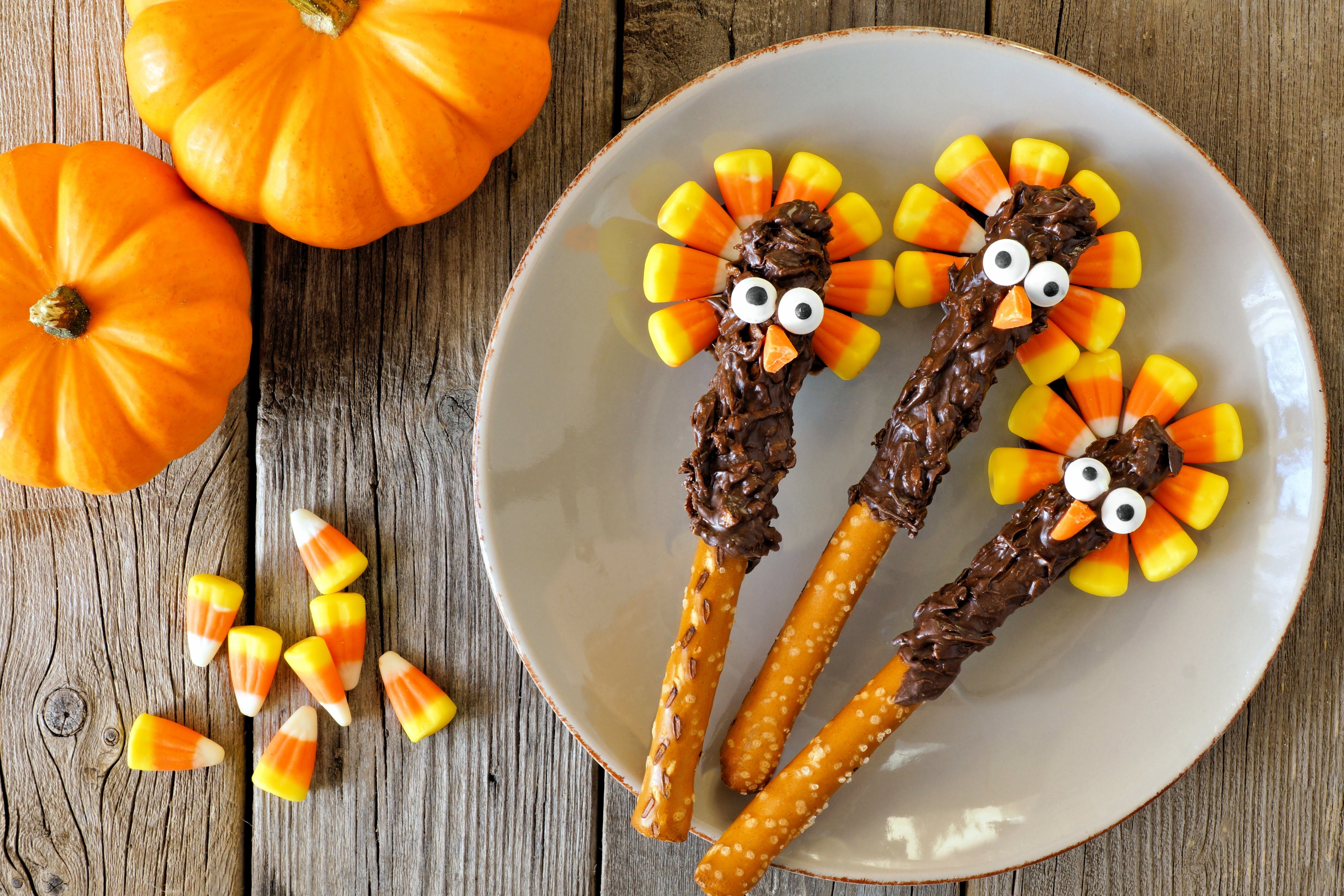 Cute Thanksgiving turkey pretzel sticks with candy corn, overhead scene on old wood