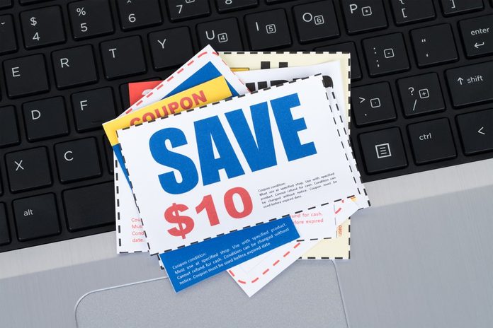 Saving discount coupon voucher on notebook keyboard, coupons are mock-up