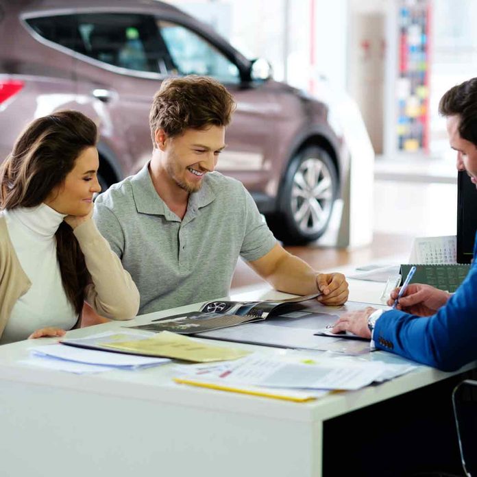 Beautiful-young-couple-reading-a-booklet-at-the-dealership-showroom
