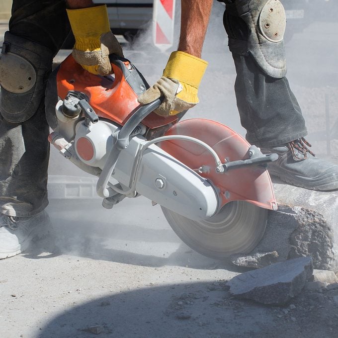 man sawing into block of concrete with large saw