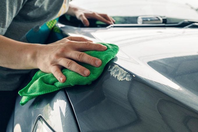 Man cleaning scratch on car with microfiber cloth and cleaner remover