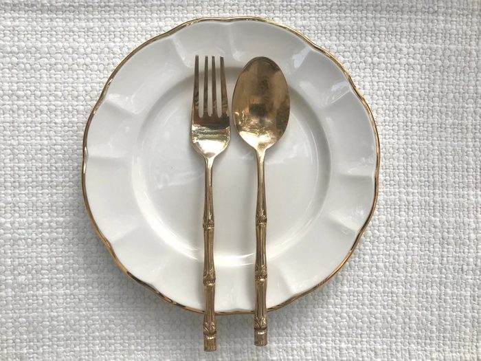Empty white plate, fork and spoon on table