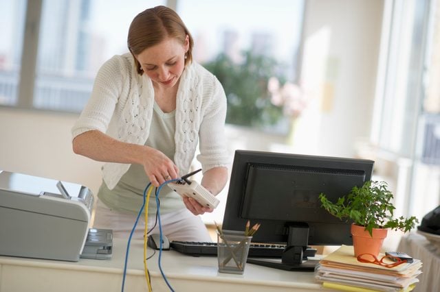 USA, New Jersey, Jersey City, woman installing router at home office