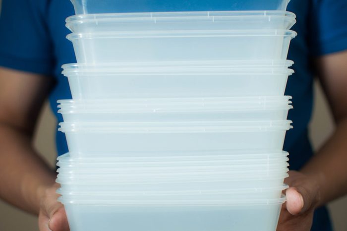 A young man is holding a recyclable plastic food container on a white background