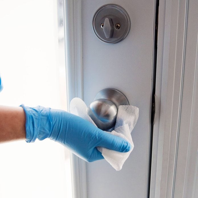 Hands with glove wiping doorknob antibacterial wipe