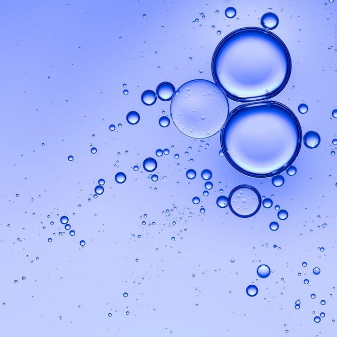 Oil drops and bubbles floating over water with a blue background