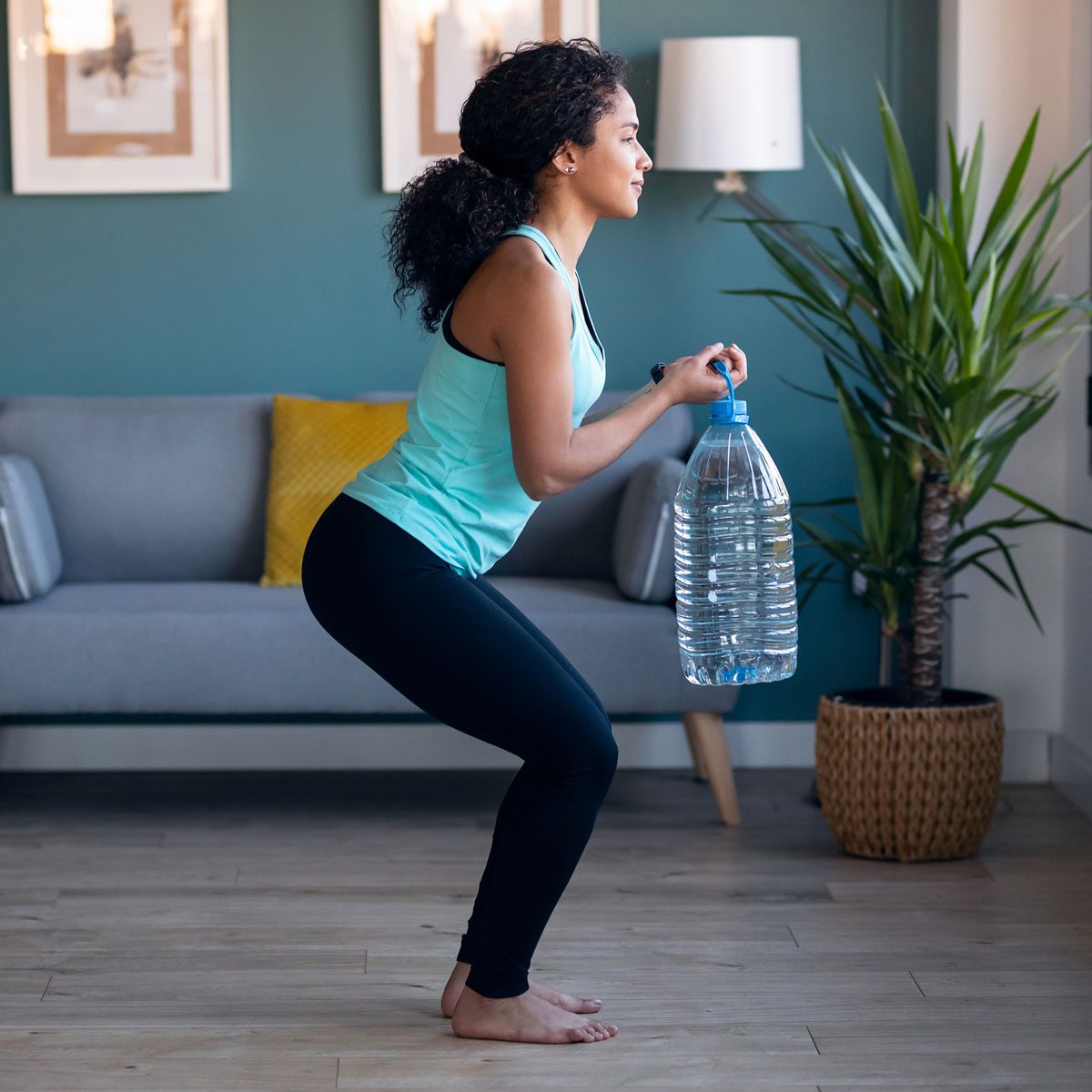 Woman squatting with Bottle Weight Gettyimages 1299959870