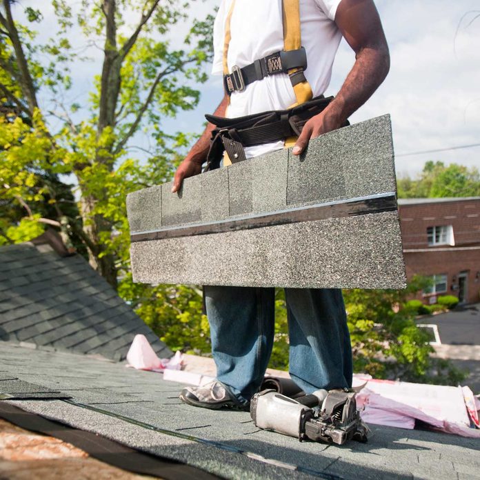 Carpenter aligning shingles on the new roof