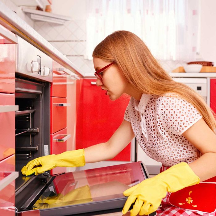 Woman cleaning a red oven