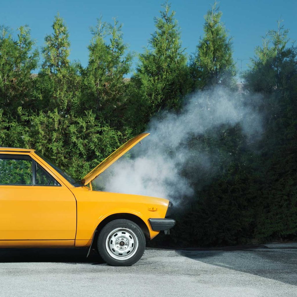 Smoke emitting from a car engine of a yellow car