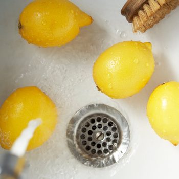 Cleaning lemons with vegetable brust in sink, elevated view