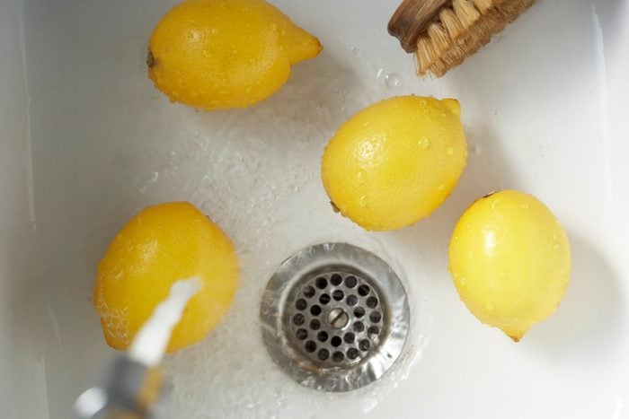 Cleaning lemons with vegetable brust in sink, elevated view