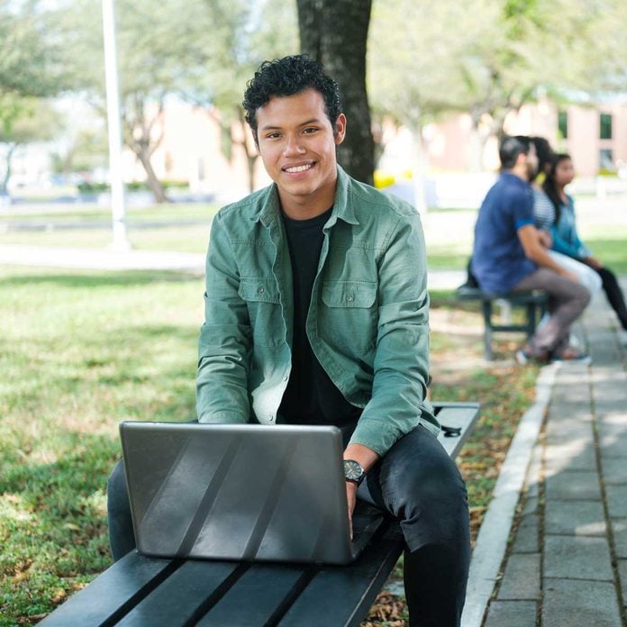 College student sitting outside with a laptop