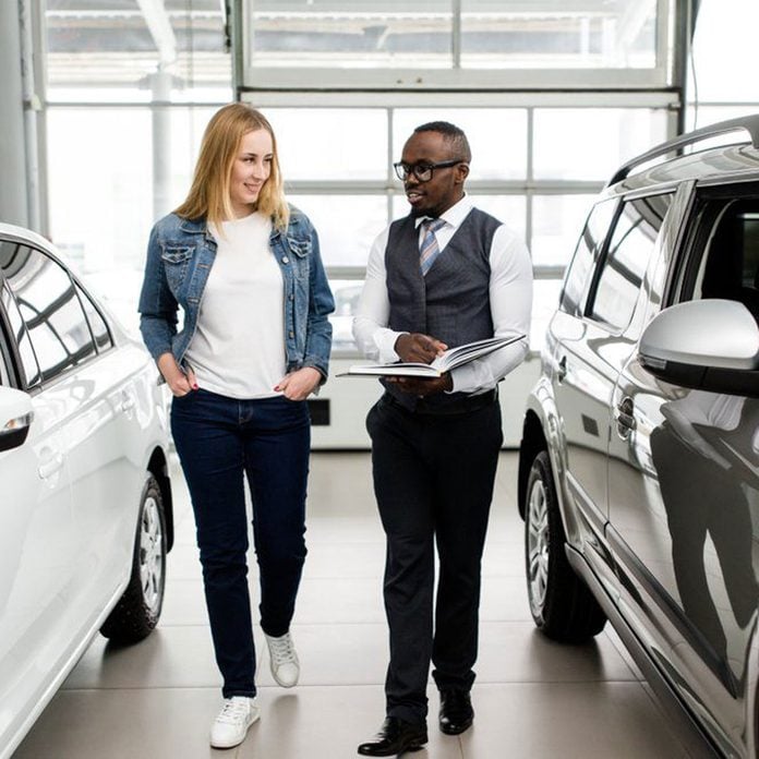 Sales Manager shows the woman new cars in the showroom