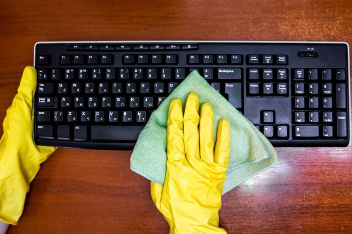 Woman in rubber gloves disinfects the keyboard