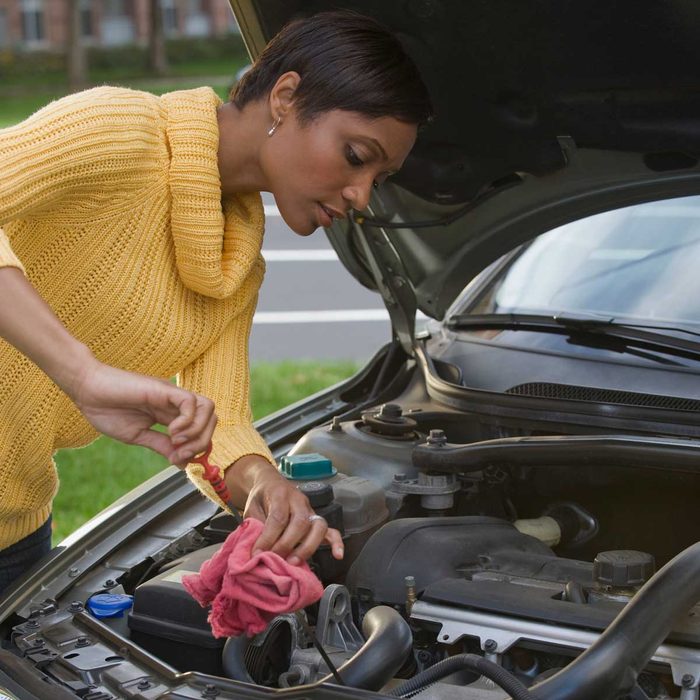 Woman checking car oil