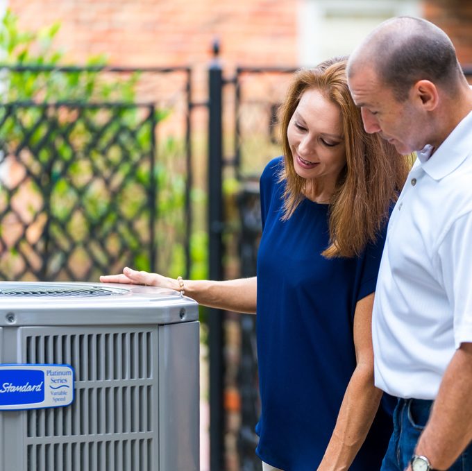 Two people checking out an air conditioner