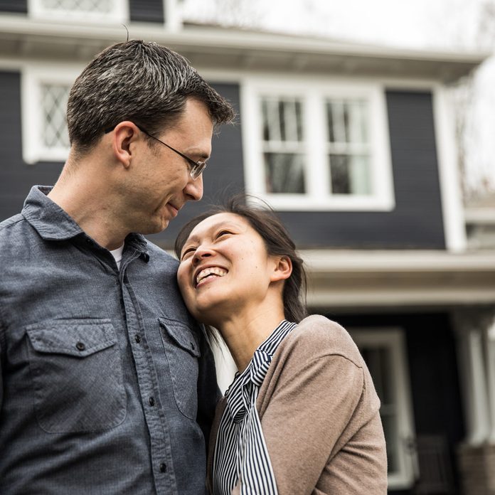 buying a home Couple standing in front of home