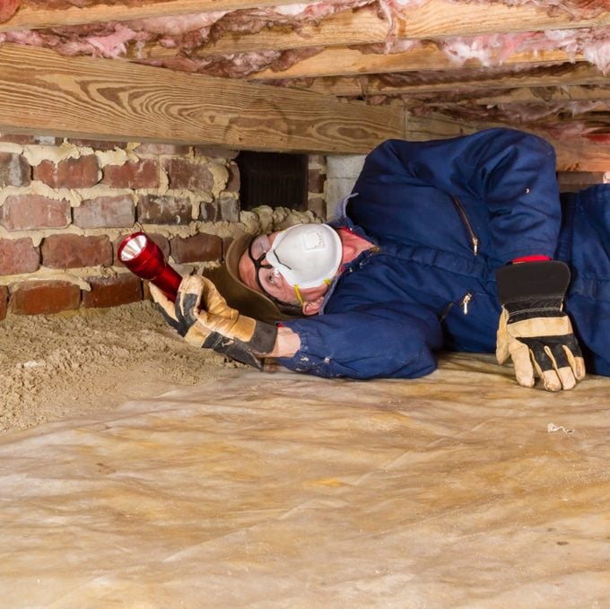 Man Inspecting For Termites In Crawl Space