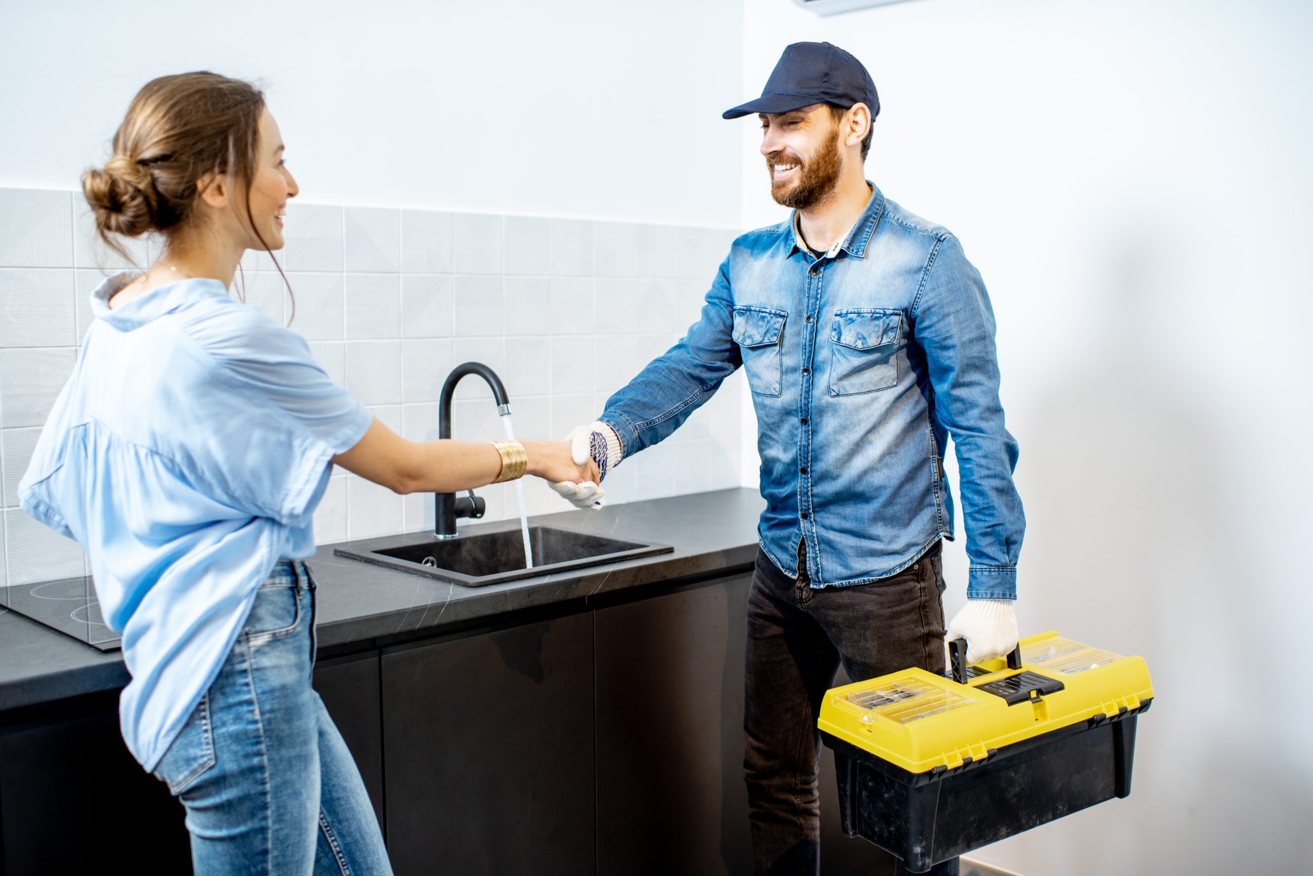 Handy man having a deal with young woman client after the repairment on the kitchen. Home repair service concept