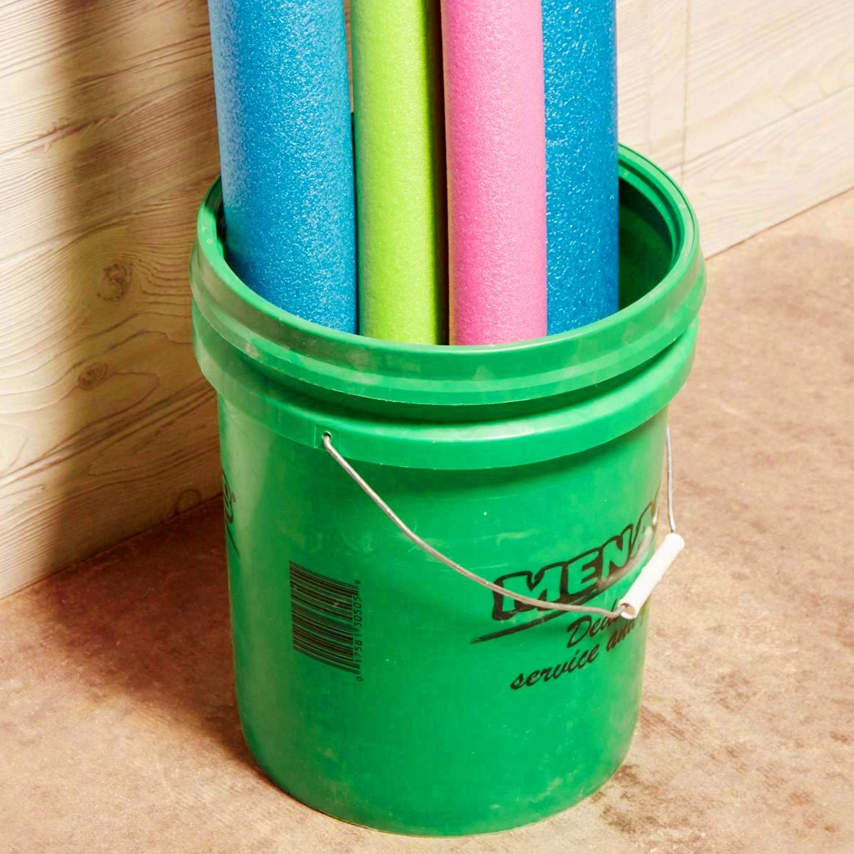 a green 5 gallon bucket filled with colorful pool noodles