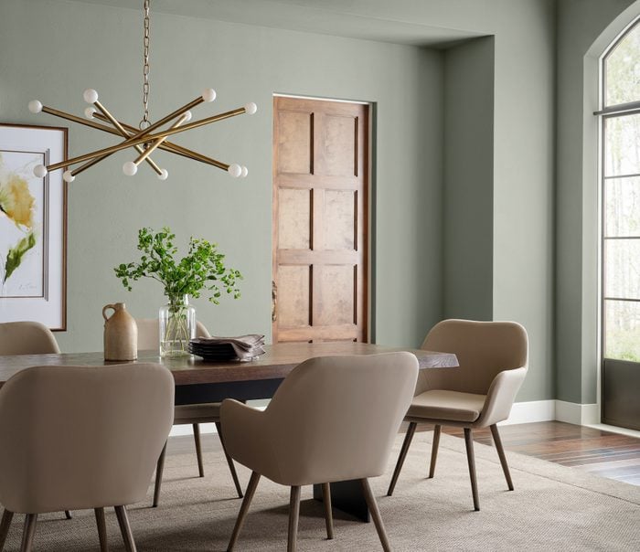 dining room table with modern hanging light, light green painted walls