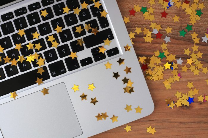 laptop keyboard with star confetti on a wooden desk