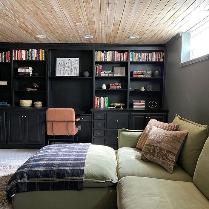 A built-in black shelf in a bedroom with a green bed and couch