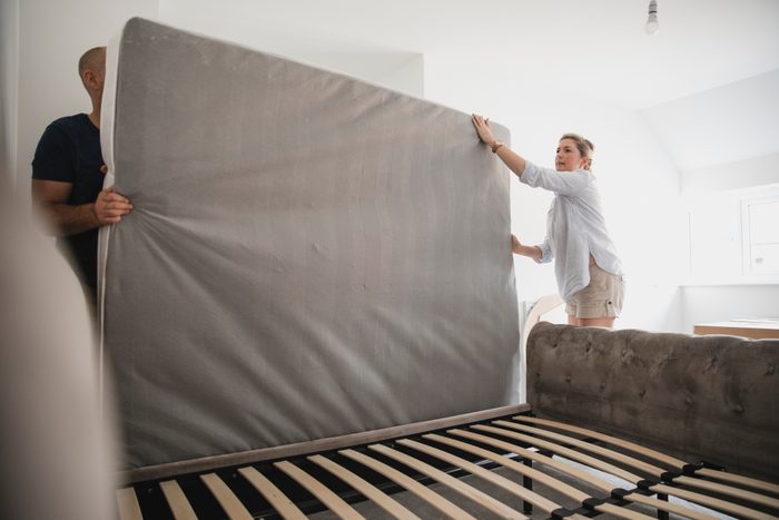 couple flipping and rotating mattress in bedroom
