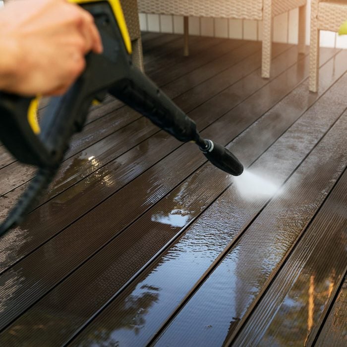 cleaning wooden terrace planks with high pressure washer