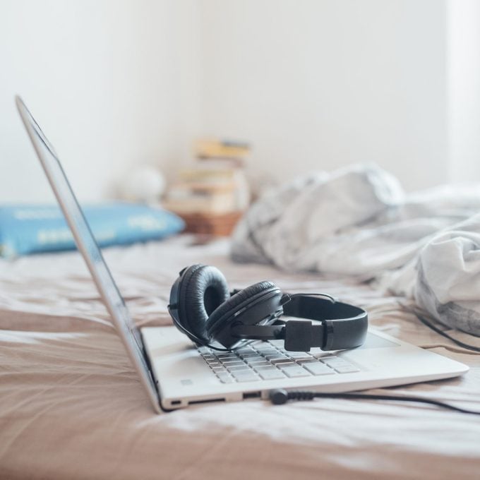 headphone and laptop on top of bed at home