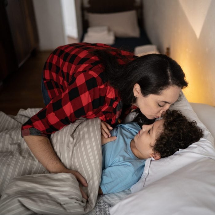 Mother putting son to sleep at home
