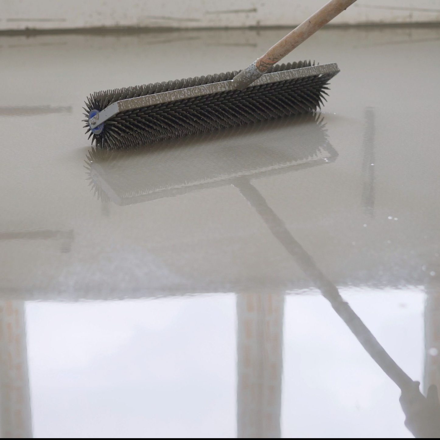 Leveling the floors with a cement mixture. Needle roller for self-leveling floor. Epoxy concept. concrete floor. on the horizon. close-up. needle roller to remove air bubbles. there is toning. then there will be painting. Needle roller for self-leveling