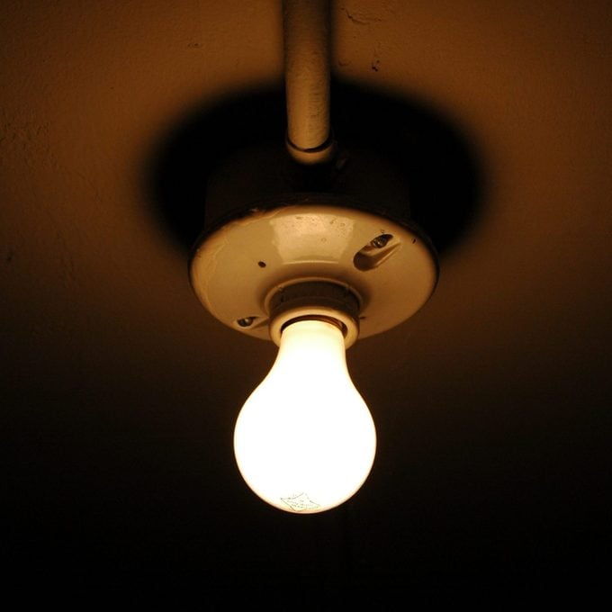 exposed light bulb on ceiling in dark closet at home