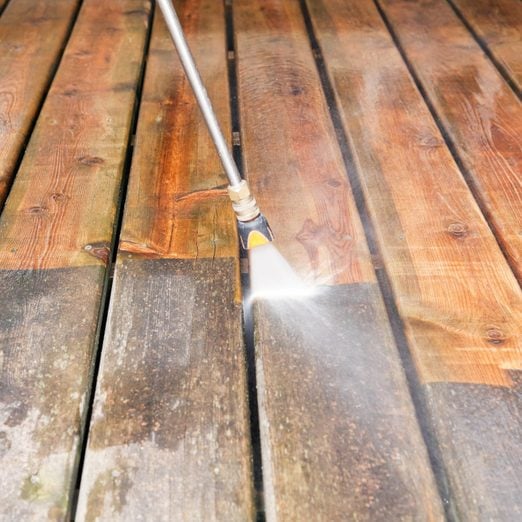Pressure Washer Cleaning a Weathered Deck