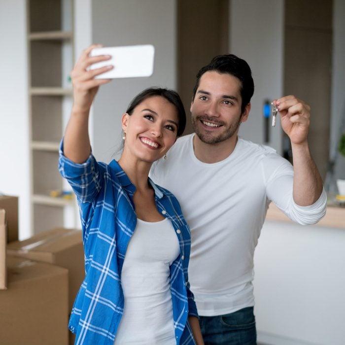 Couple taking a selfie holding keys to their new house