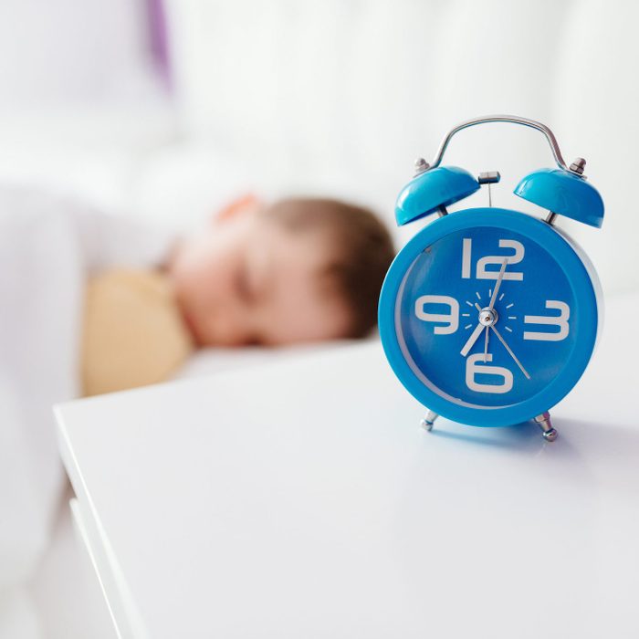 alarm clock on table next to young boy sleeping