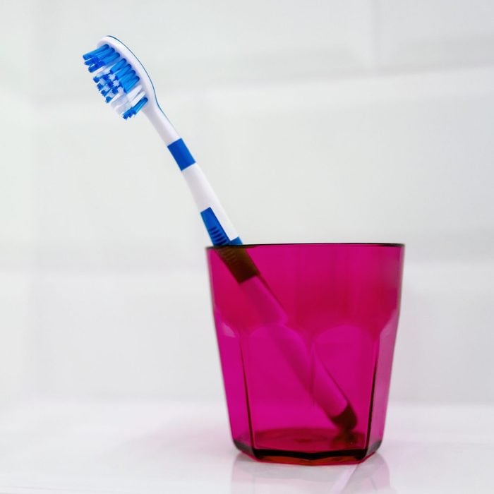 Blue toothbrush in pink toothbrush holder