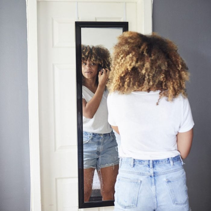 young person looking in a mirror that is hanging on a door in a dorm room