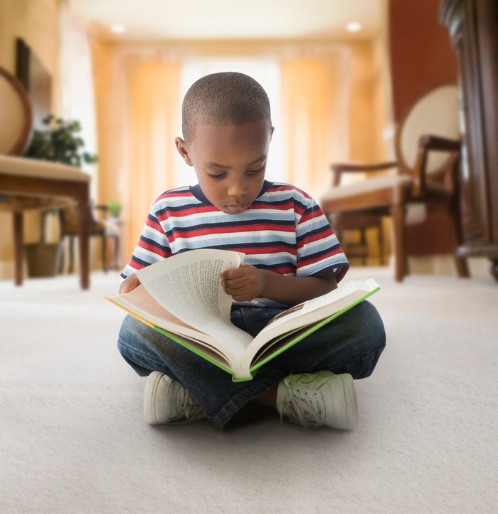 African American boy reading on floor