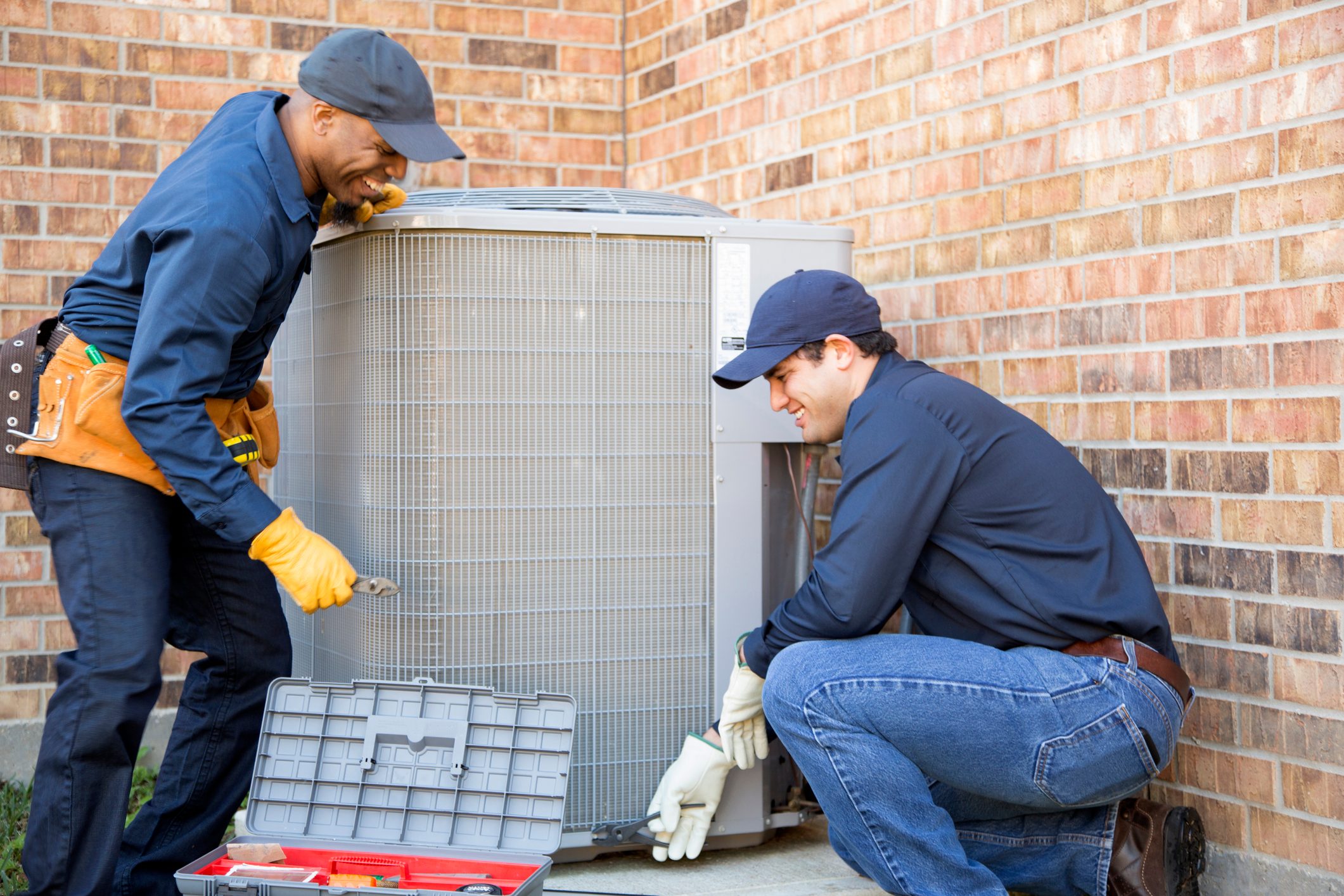 team of hvac installers repairing central air conditioning system outside of house