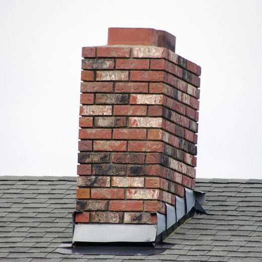 A brick small chimney on a the roof of home