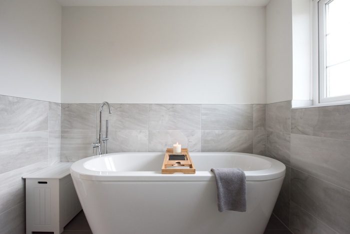 luxurious white bath tub in gray bathroom of home