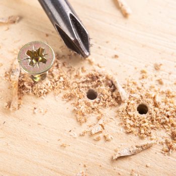 Screwing metal screws into pilot holes drilled into chipboard for furniture construction.