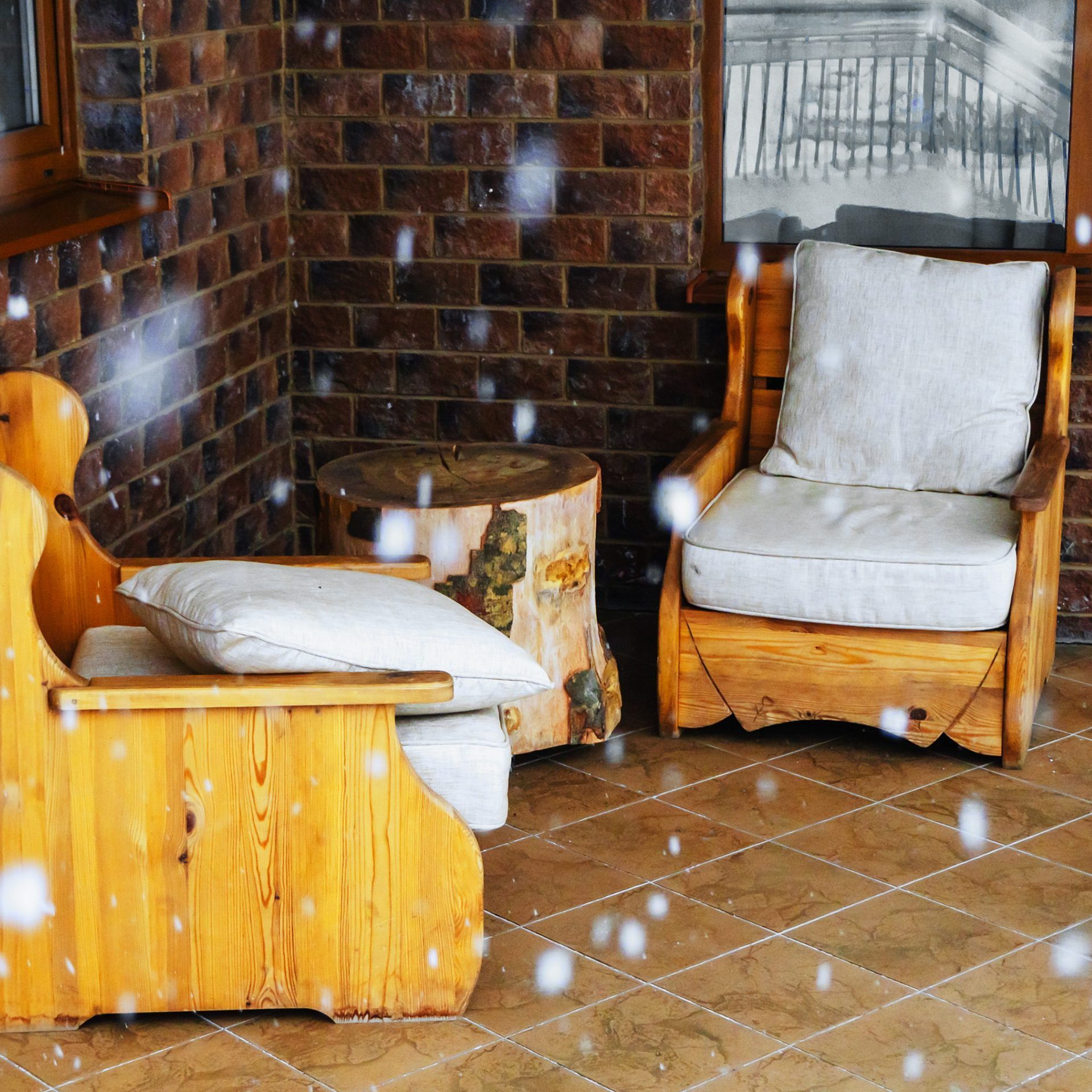 Wooden armchairs with cushions on a covered patio during a snowfall