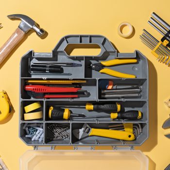 Opened DIY Toolbox With a Collection of Tools on a yellow background